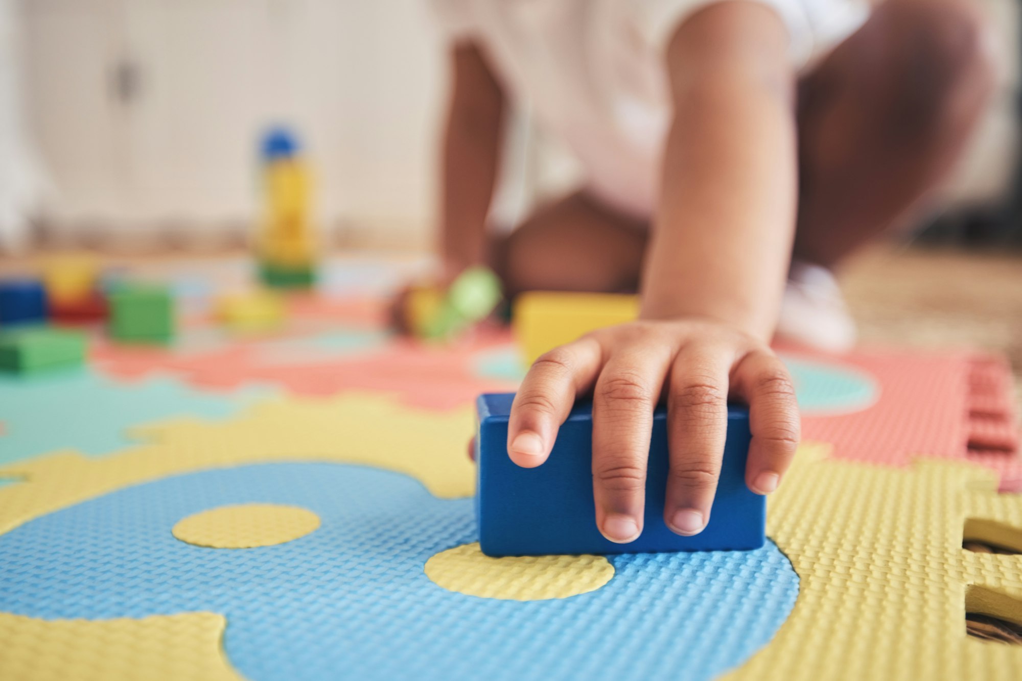 Building blocks, hands and toddler at daycare with development on number carpet and ground. Learnin